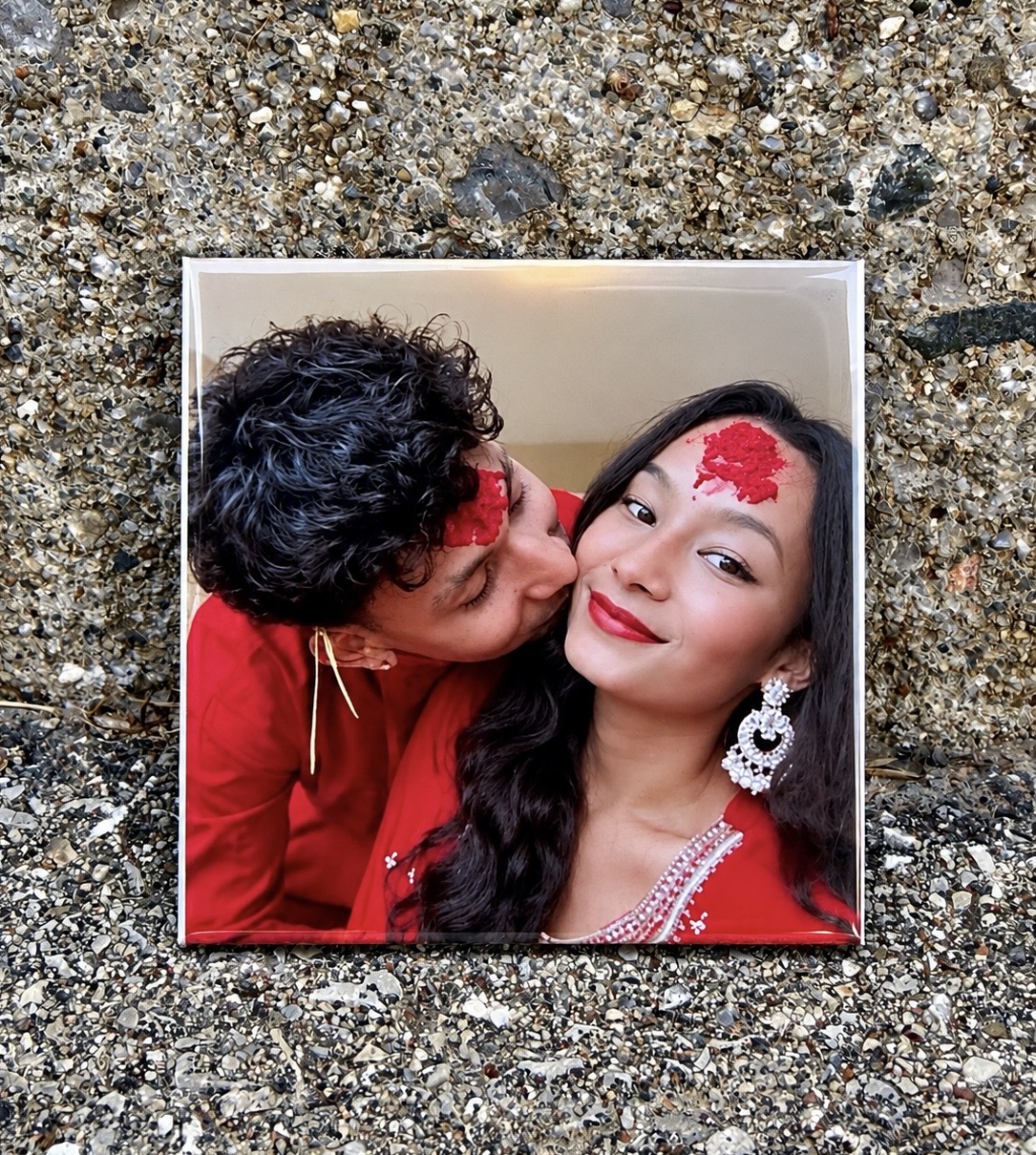 A glossy photo magnet of a couple in red traditional outfits