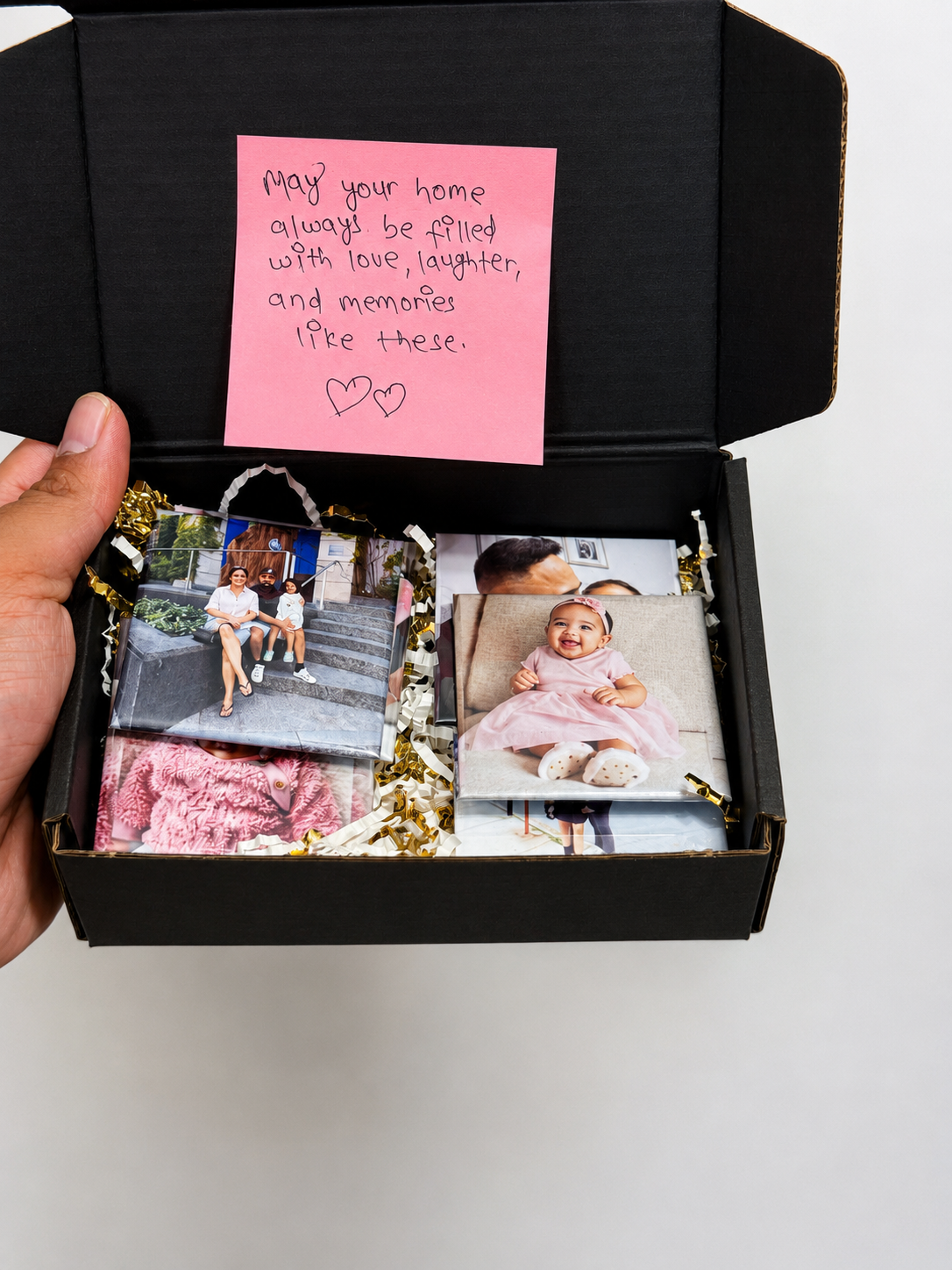 An open gift box with a handwritten note and finished photo magnets